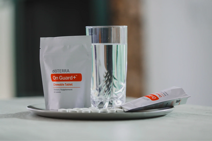 Sachet de comprimés à croquer On Guard+ et verre d'eau posés sur un plateau