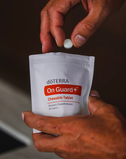 Main prenant un comprimé à croquer On Guard+ dans son sachet dōTERRA