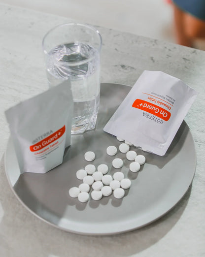 Comprimés à croquer On Guard+ sur un plateau, avec deux sachets et un verre d'eau