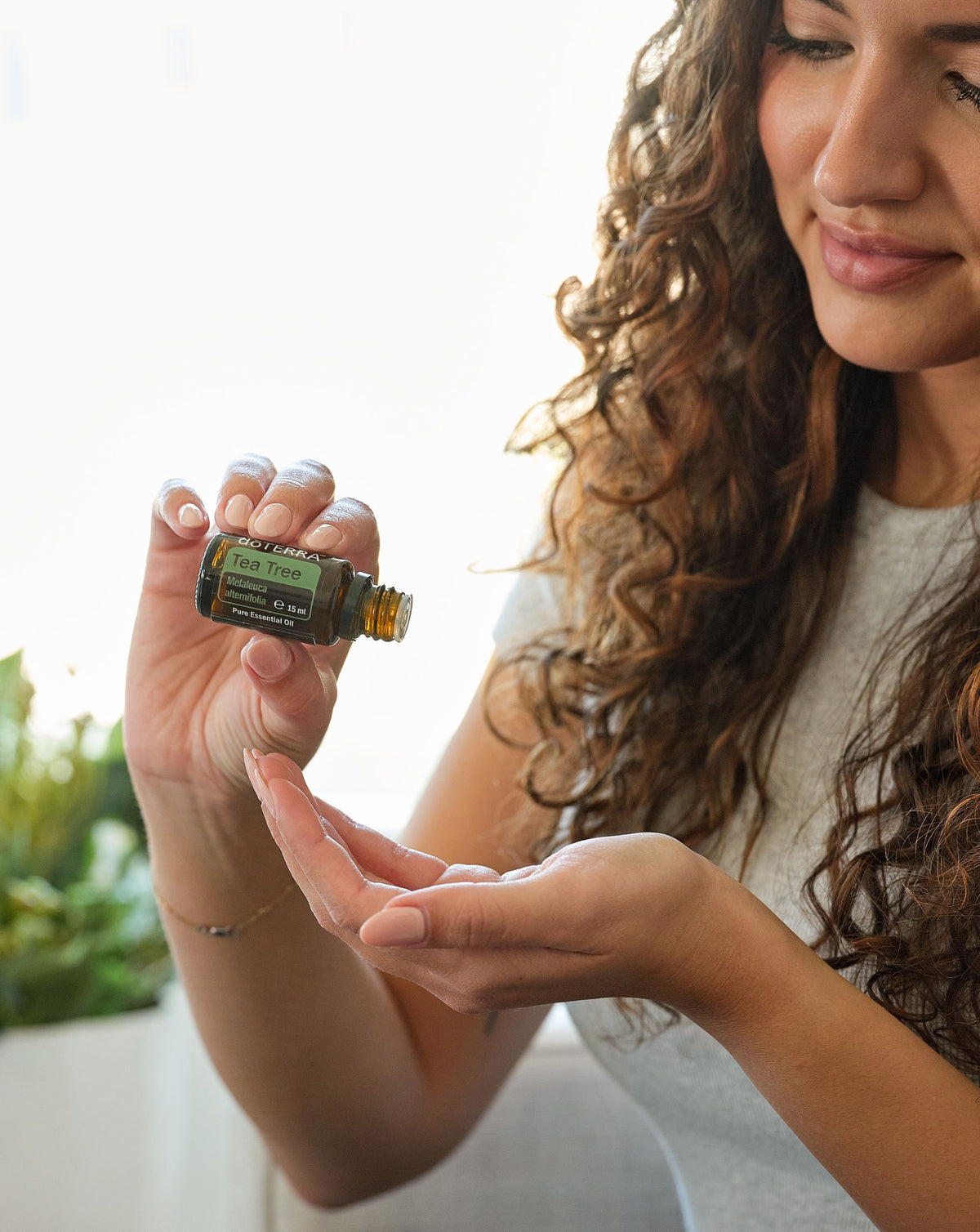 Arbre à thé huile essentielle dōTERRA, femme versant une goutte dans sa main