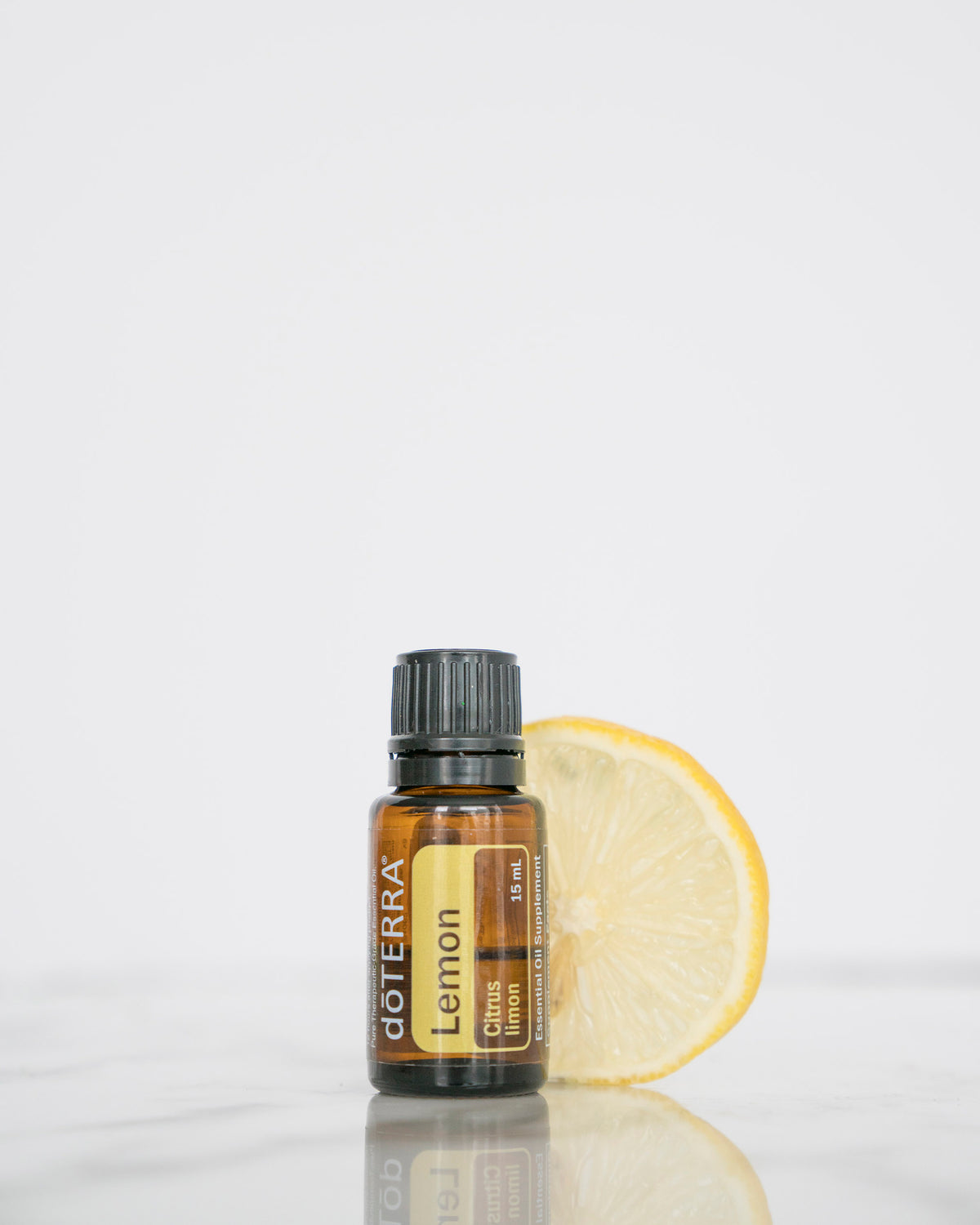 Citron huile essentielle dōTERRA, avec une tranche de citron sur fond blanc