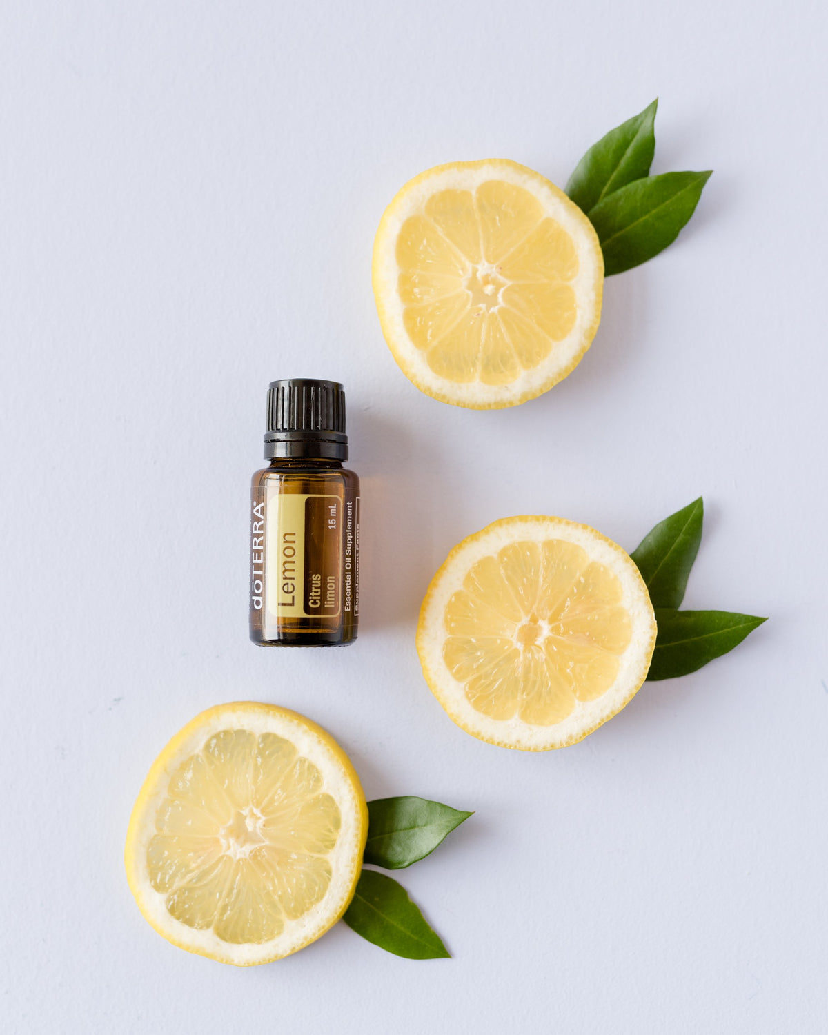 Citron huile essentielle dōTERRA, avec des tranches de citron et des feuilles