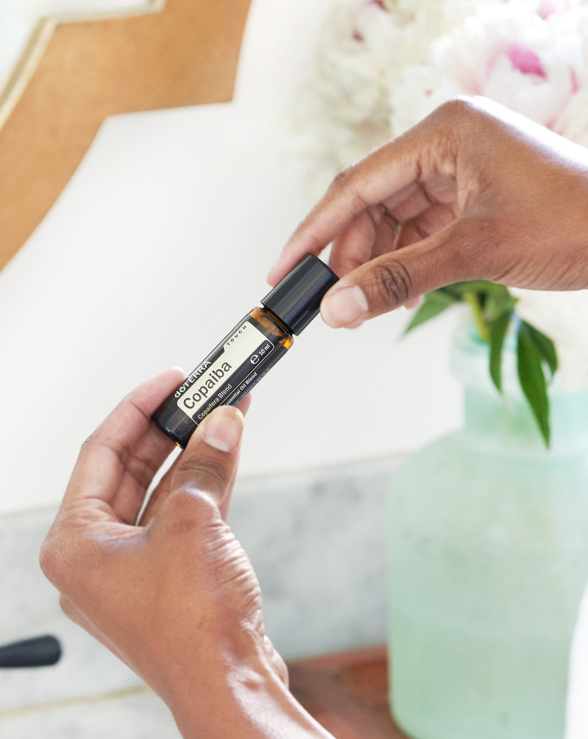 Copaiba Touch dōTERRA, flacon à bille tenu entre les mains