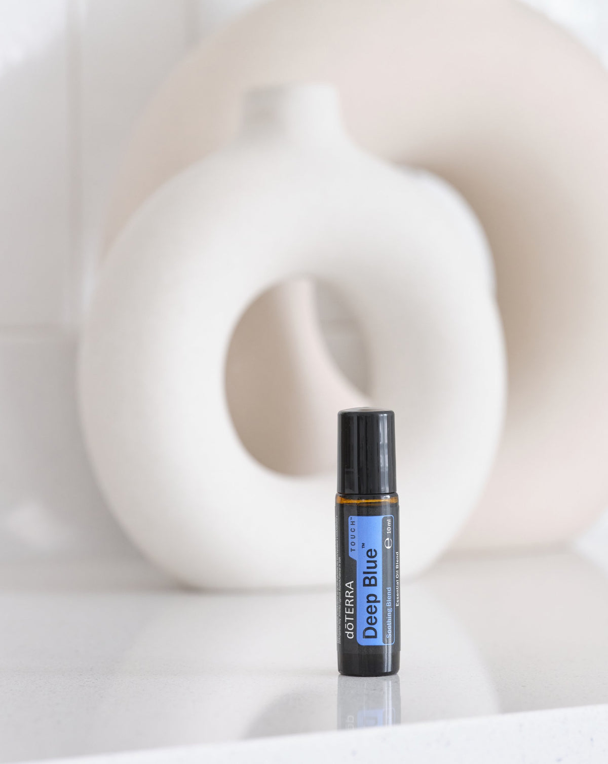 Deep Blue Touch mélange en applicateur à bille dōTERRA, roll-on devant un vase blanc