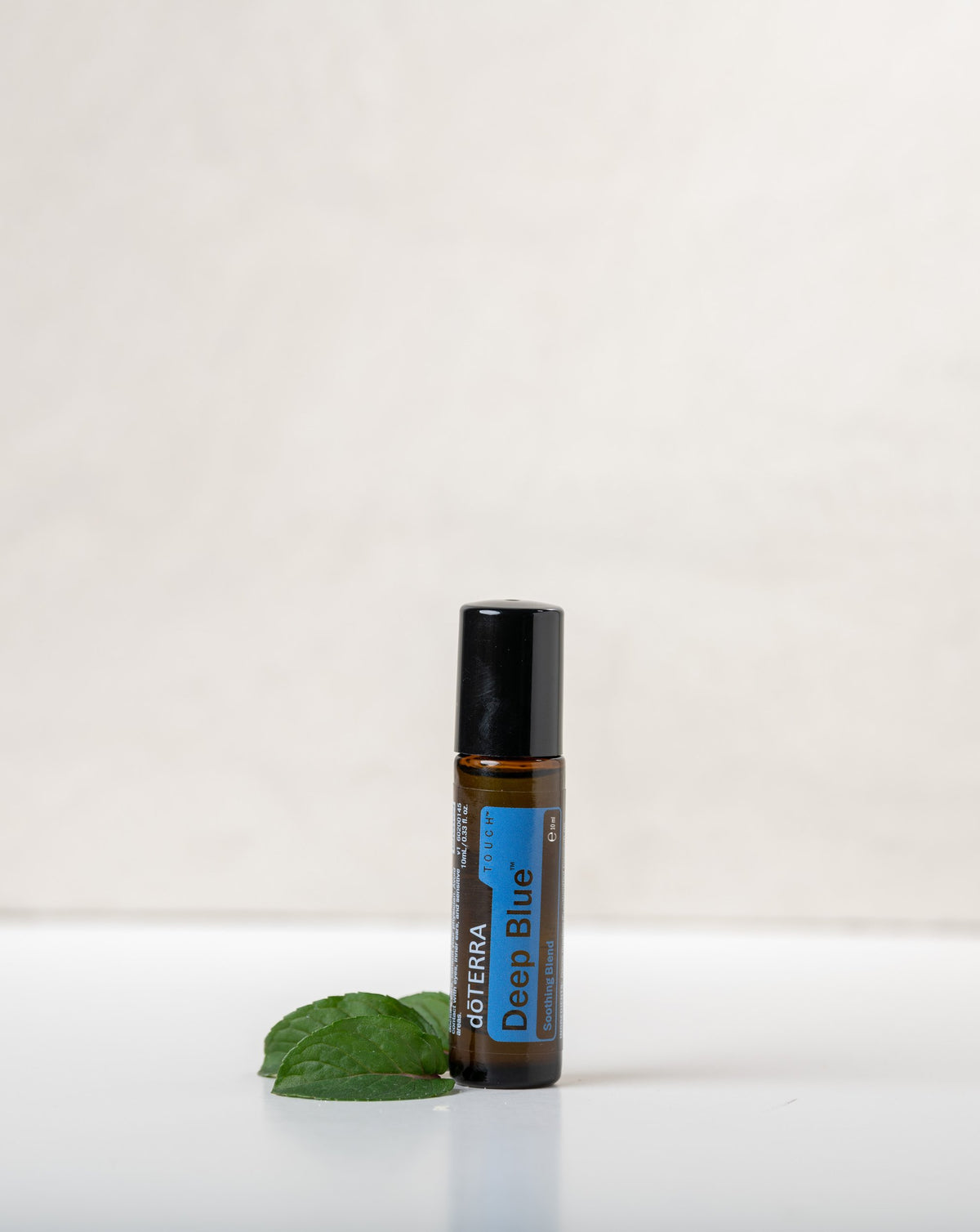 Deep Blue Touch mélange en applicateur à bille dōTERRA, roll-on avec une feuille sur fond clair