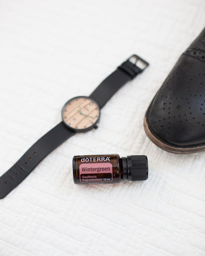 Gaulthérie huile essentielle dōTERRA, à côté d'une montre de sport