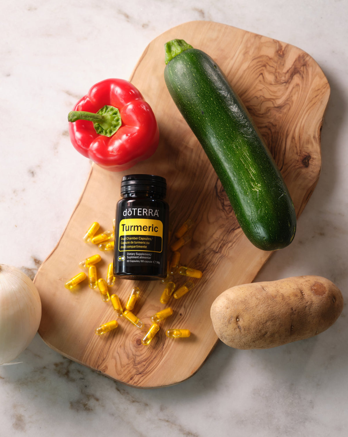 Gélules doubles au Curcuma dōTERRA, flacon sur planche avec légumes