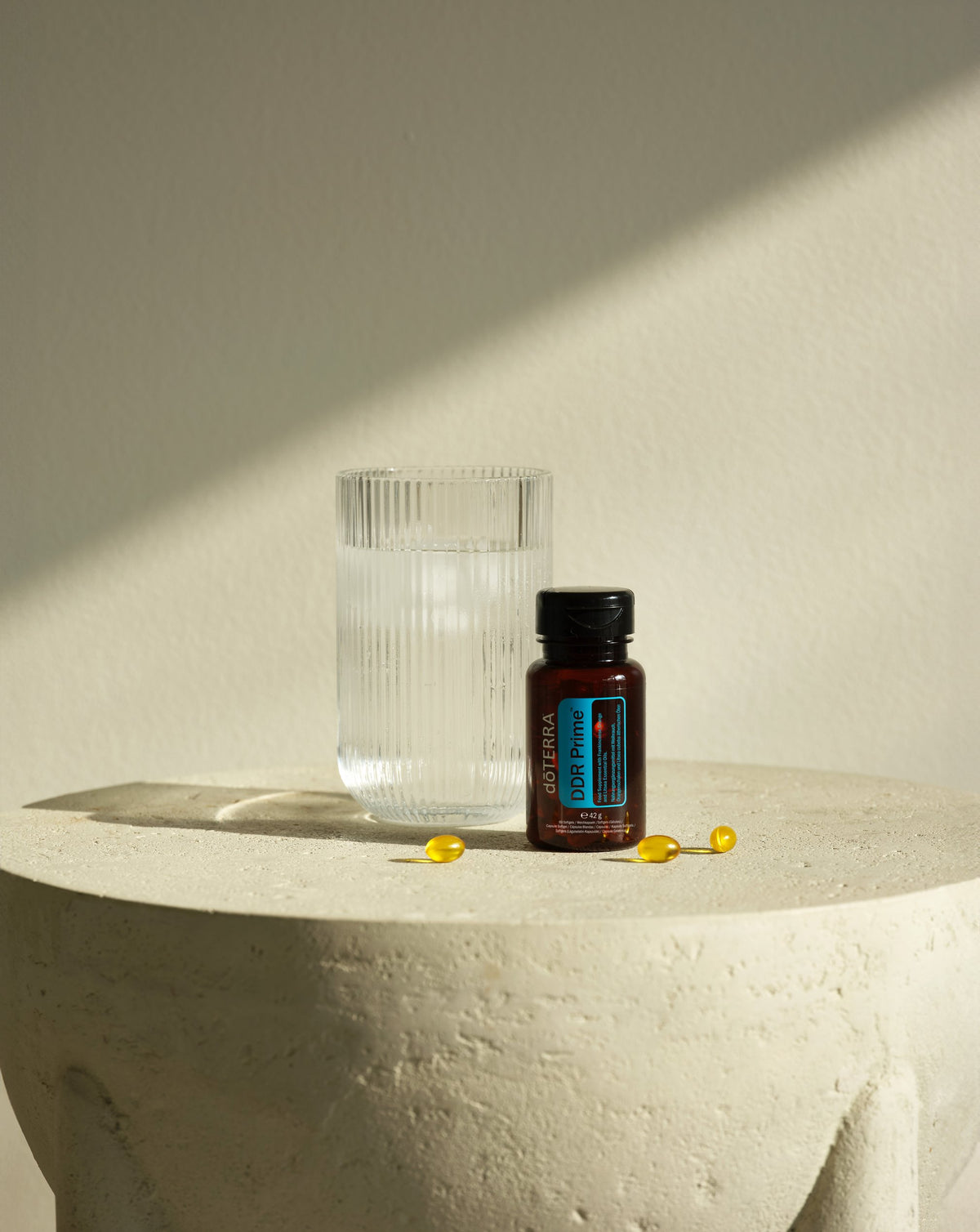 DDR Prime dōTERRA, flacon et verre sur une sellette