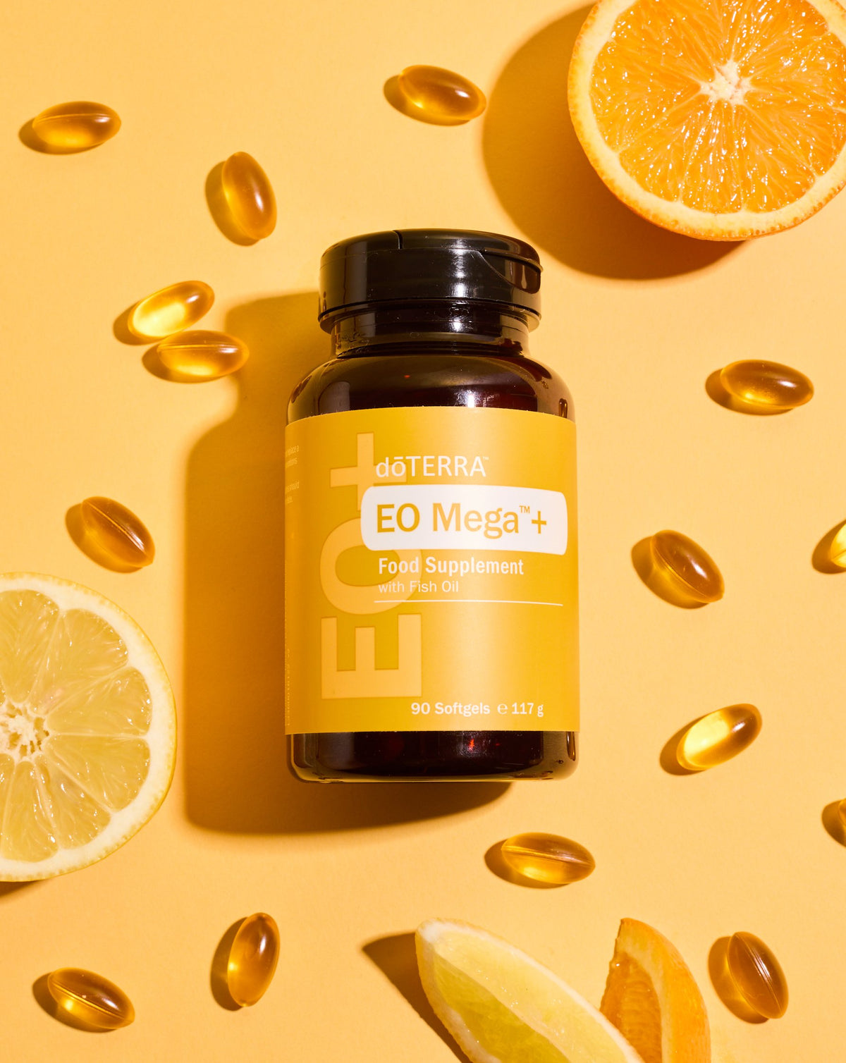 Gélules EO Mega+ dōTERRA, flacon sur fond jaune avec agrumes