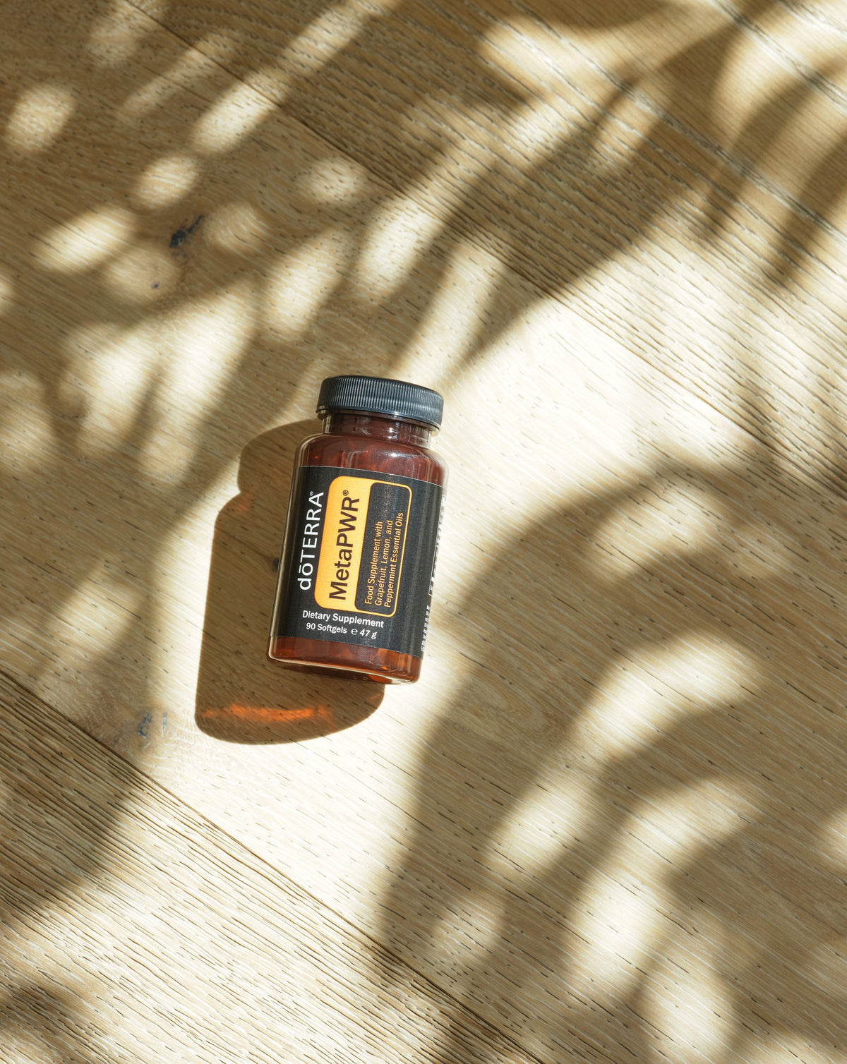 Gélules MetaPWR dōTERRA, flacon dans les ombres de feuillage