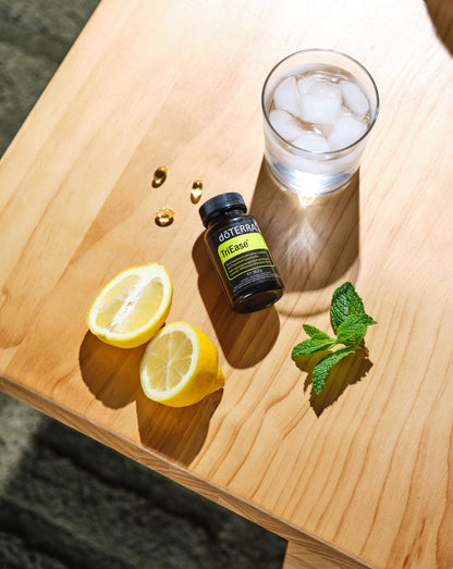 Gélules TriEase dōTERRA, flacon sur planche avec citron et menthe