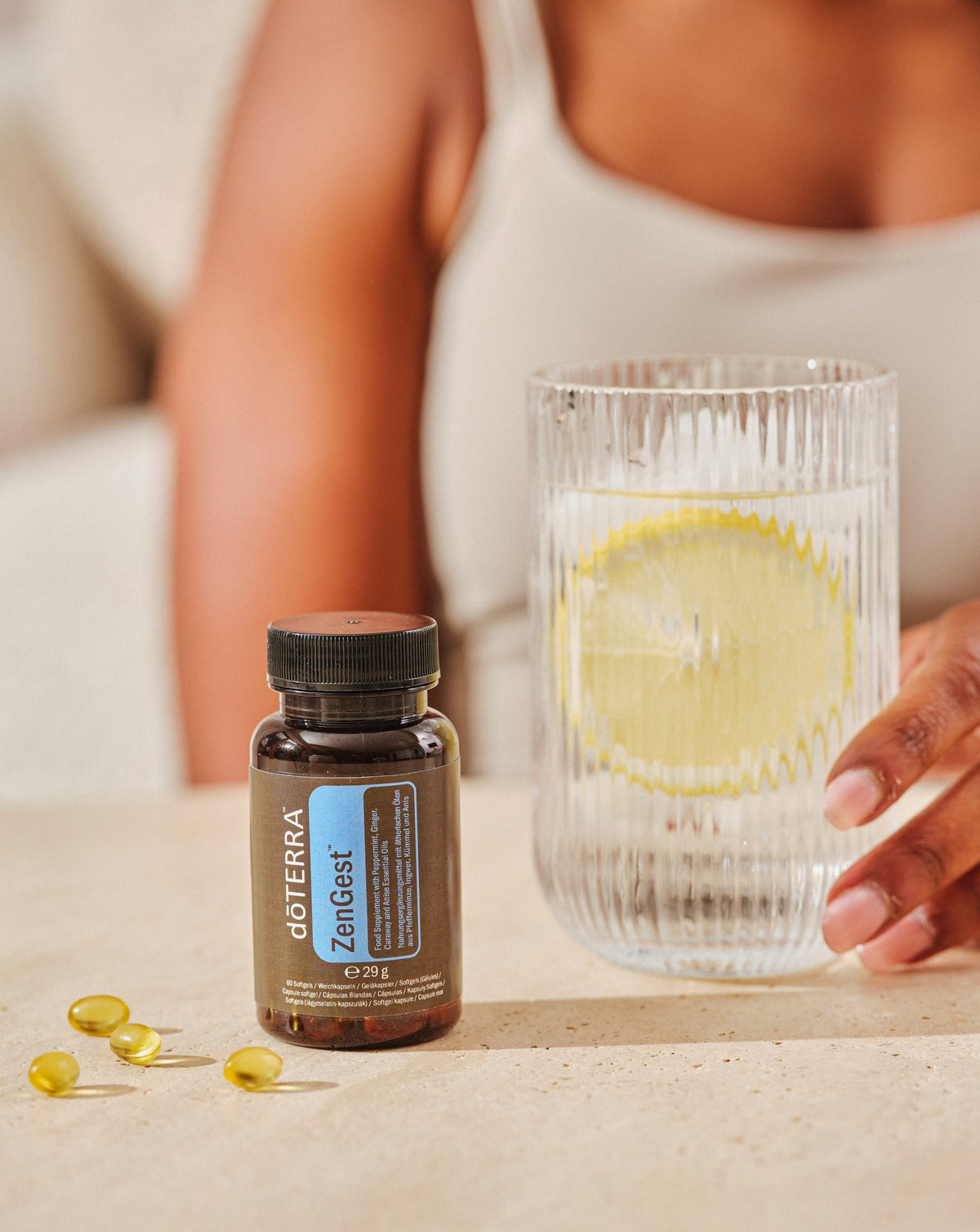 Gélules ZenGest dōTERRA, flacon et verre d'eau citronnée