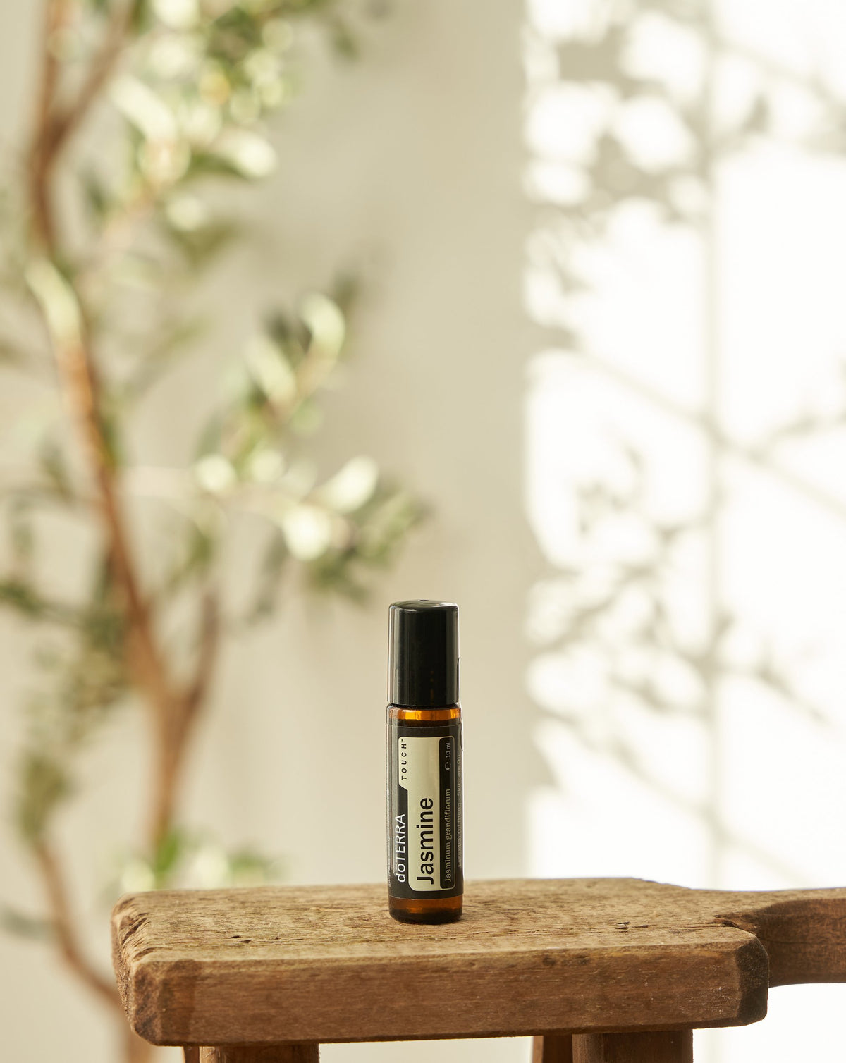 Jasmin Touch dōTERRA, flacon sur une tablette en bois près d'une plante
