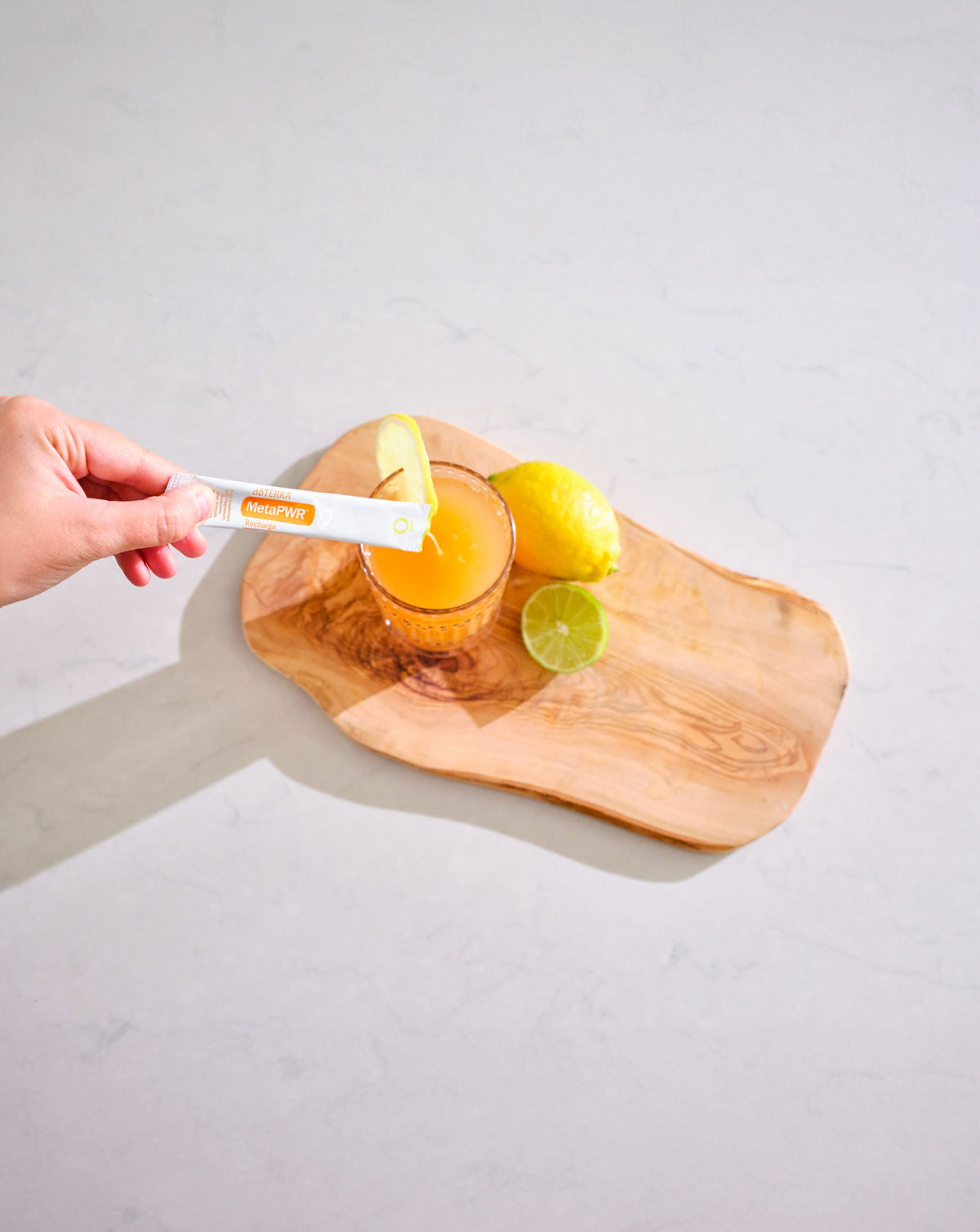 MetaPWR Recharge citron - citron vert dōTERRA, sachet versé dans un verre sur une planche