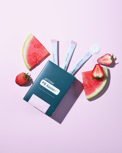 PB Assist+ dōTERRA, boîte et sachets sur fond rose