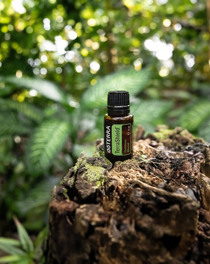 TerraShield dōTERRA, flacon sur une souche moussue en forêt