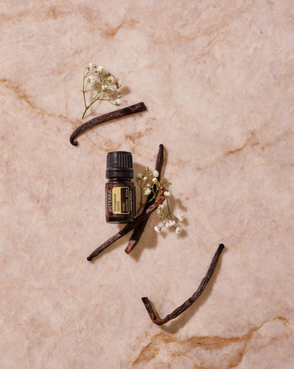 Vanille de Madagascar dōTERRA, flacon et gousses de vanille sur marbre rose