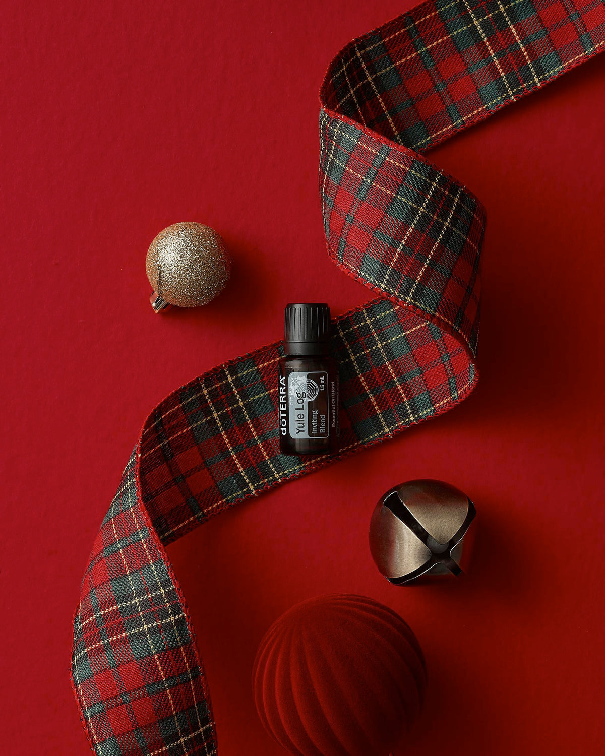 Yule Log mélange d'huiles essentielles dōTERRA, flacon sur fond rouge